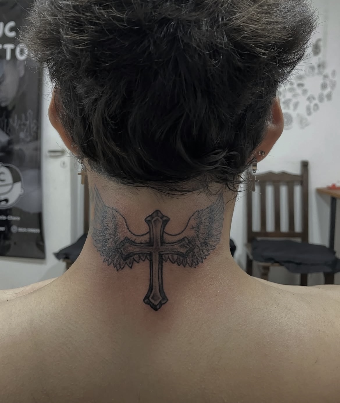 Tatuaje de cruz con alas en la nuca realizado en JC TATUAJES
